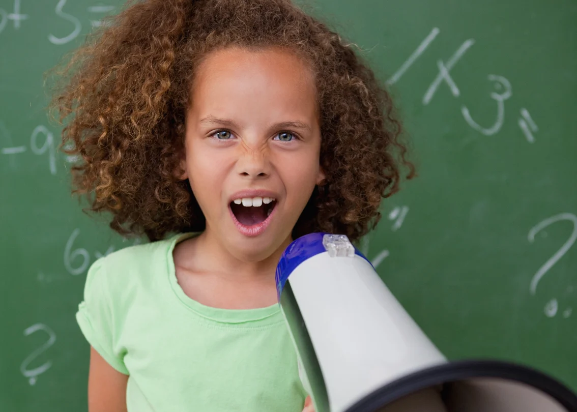 Portrait of a young schoolgirl screaming through a megaphone