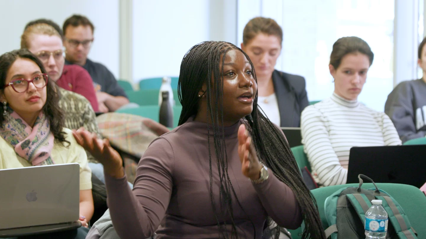 Masters student sat in a seminar room with other course students