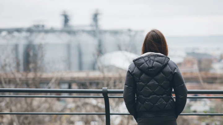 A woman is standing on a railing looking out over a city